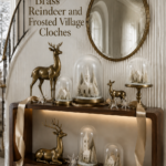 Brass reindeer Christmas console with frosted village cloches champagne ribbon glass stars and an antique oval mirror