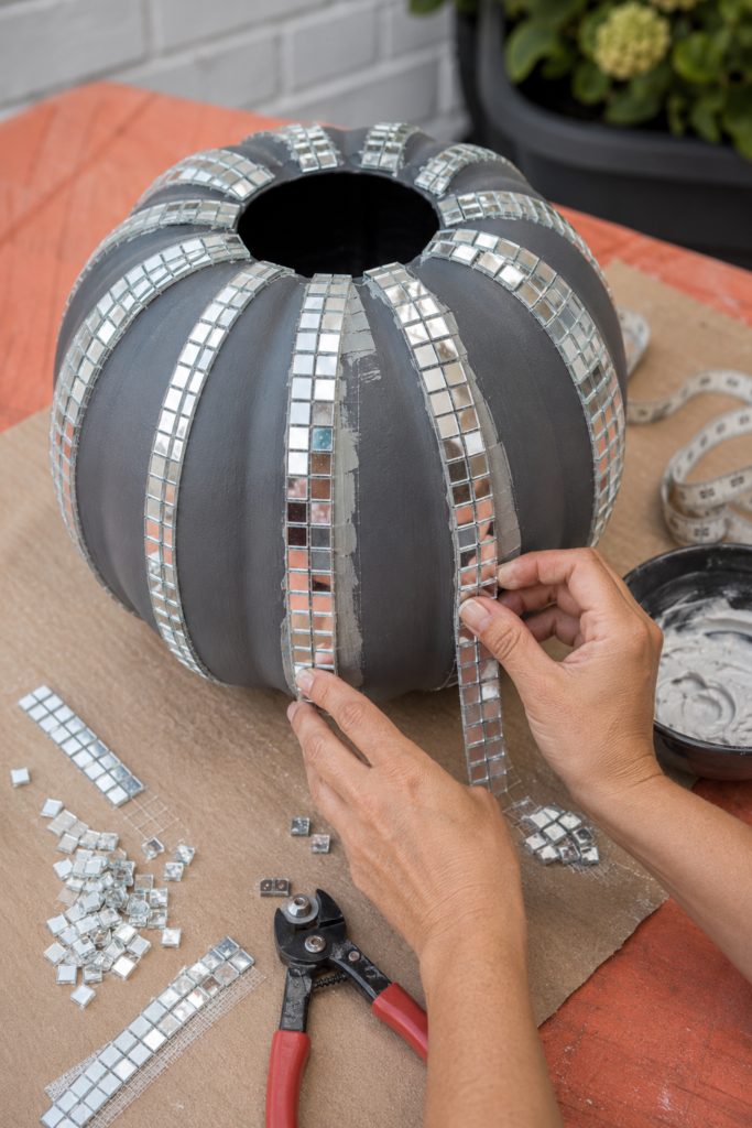 Dry-fitting silver mosaic tiles on a pumpkin
