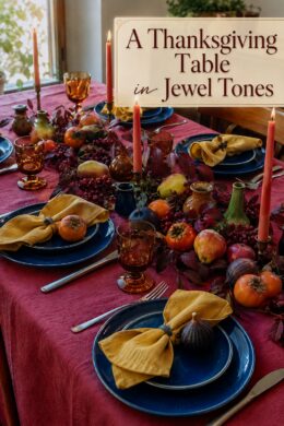 Thanksgiving fruit and foliage tablescape with cranberry linens and jewel tone table
