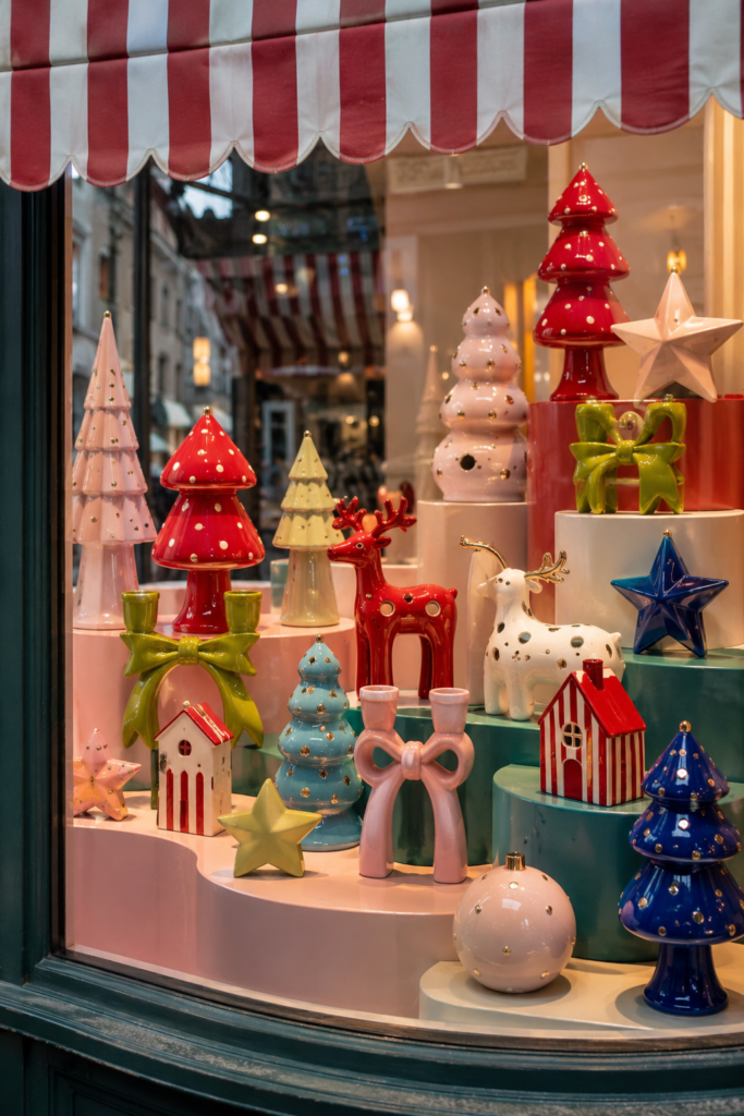 brightly colored Christmas figurines with star trees and reindeer in store window