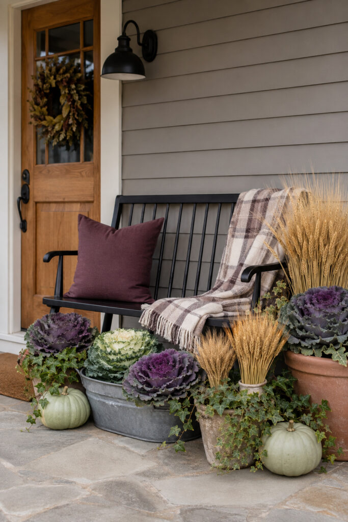 fall porch bench surrounded by purple ornamental cabbage wheat ivy and pale sage pumpkins