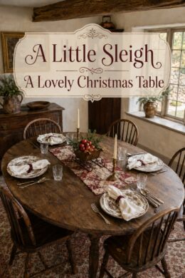Cottage Christmas dining table with mixed patterned dishes and a sleigh centerpiece beneath text reading A Little Sleigh A Lovely Christmas Table