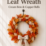 Fall Wreath with fake leaves in orange rust and cream with 3 copper bells hanging from a cream bow at the bottom
