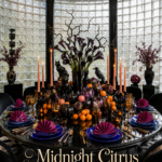 Round black table with citrus and Halloween figures beside cobalt place settings beneath ivory text reading Midnight Citrus A Halloween Supper
