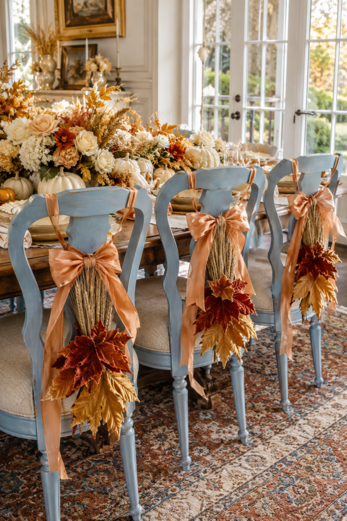 Blue Thanksgiving dining chairs decorated with wheat peach ribbon and velvet fall leaves