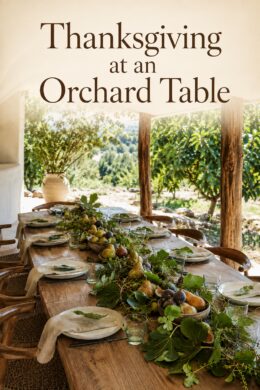 Pear and fig centerpiece on a wooden dining table overlooking leafy trees with text reading Thanksgiving at an Orchard Table