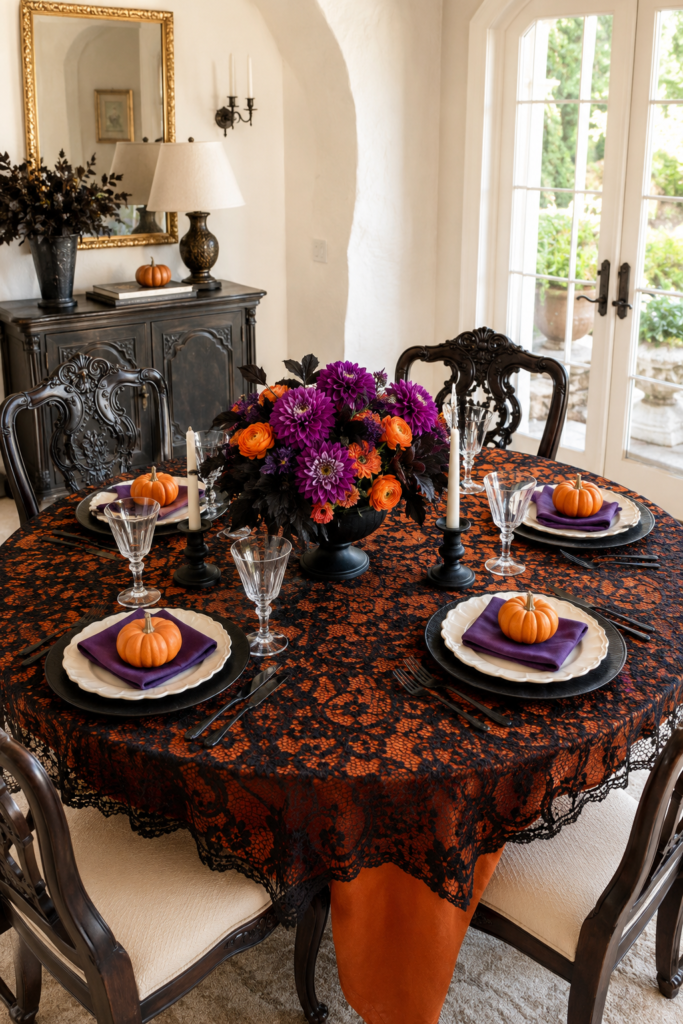 Halloween dining table with black lace over orange cloth purple flower centerpiece and mini pumpkins on four place settings
