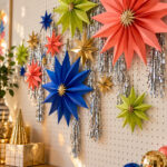 old Your Own Christmas Stars text over colorful dimensional paper stars and silver tinsel on a pegboard craft wall
