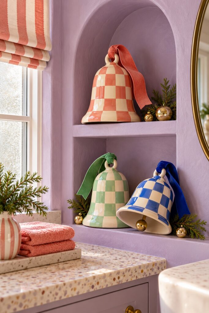 Coral mint and blue checked ceramic bells stand with cedar sprigs and gold ornaments on recessed lilac bathroom shelves